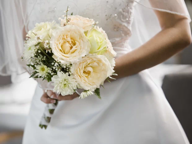 Kobieta w sukni ślubnej z bukietem białych kwiatów